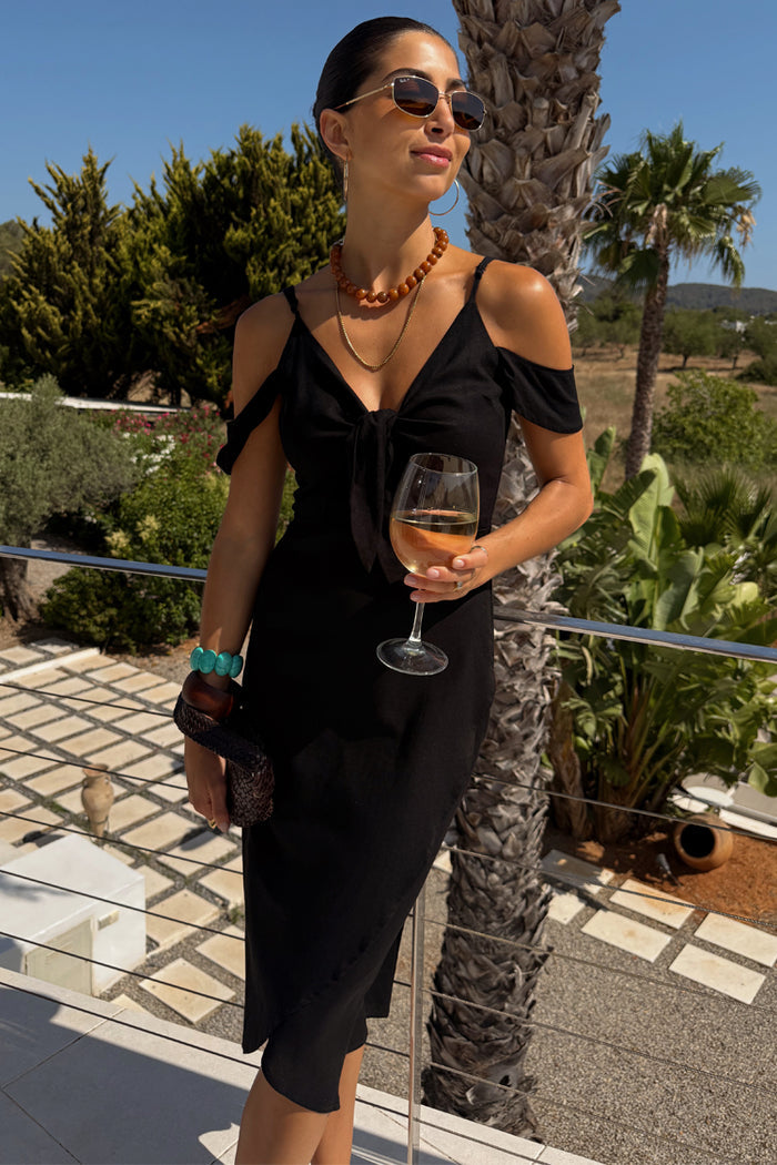 Black Cassie Dress in a multi-wear off-the-shoulder silhouette with a centre tie for a summer vacation look.