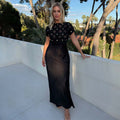 Black Crochet Shell Elodie Dress with gold shell embellishments and a black satin skirt, styled outdoors.