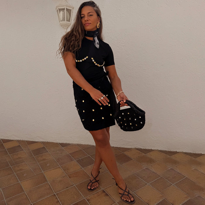 Black Crochet Shell Wrap Skirt with gold shell embellishments and a tie waist, styled for a vacation look.