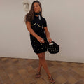 Black Crochet Shell Wrap Skirt with gold shell embellishments and a tie waist, styled for a vacation look.