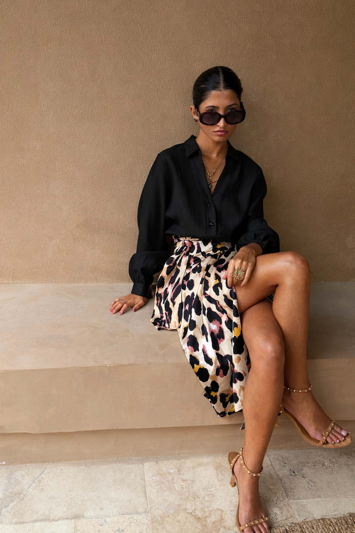 Model wearing the Black Miley Shirt with blouson sleeves and a leopard print wrap skirt.
