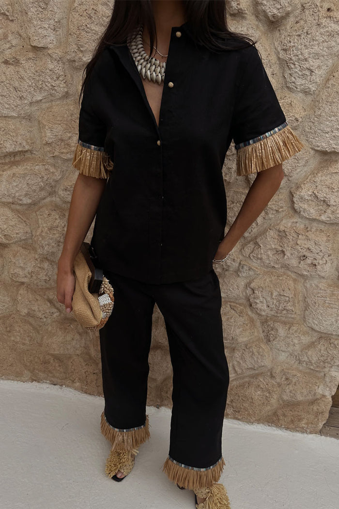 Black Raffia Marra Trousers with fringe hems, styled as a co-ord with a matching shirt and raffia clutch.