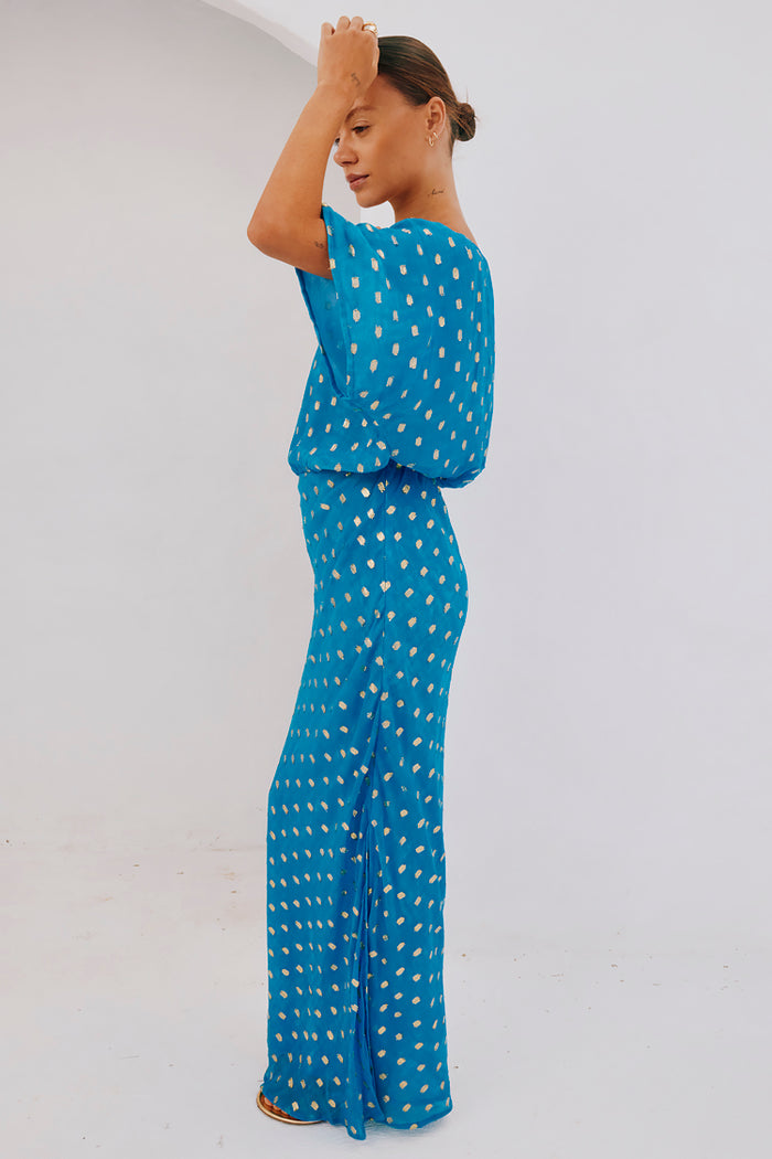 Blue Jacquard Tilly Dress with gold metallic dots and an off-the-shoulder silhouette, shown on a model from the side.