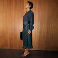 Bottle Green Vegan Leather Ruffle Jaspre Skirt styled with leopard print heels against a wooden wall.