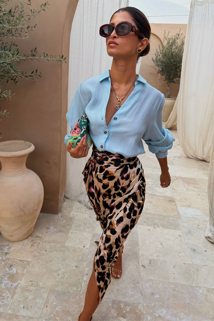 Brown Leopard Jaspre Skirt in satin with an adjustable wrap, paired with a light blue button-down shirt.