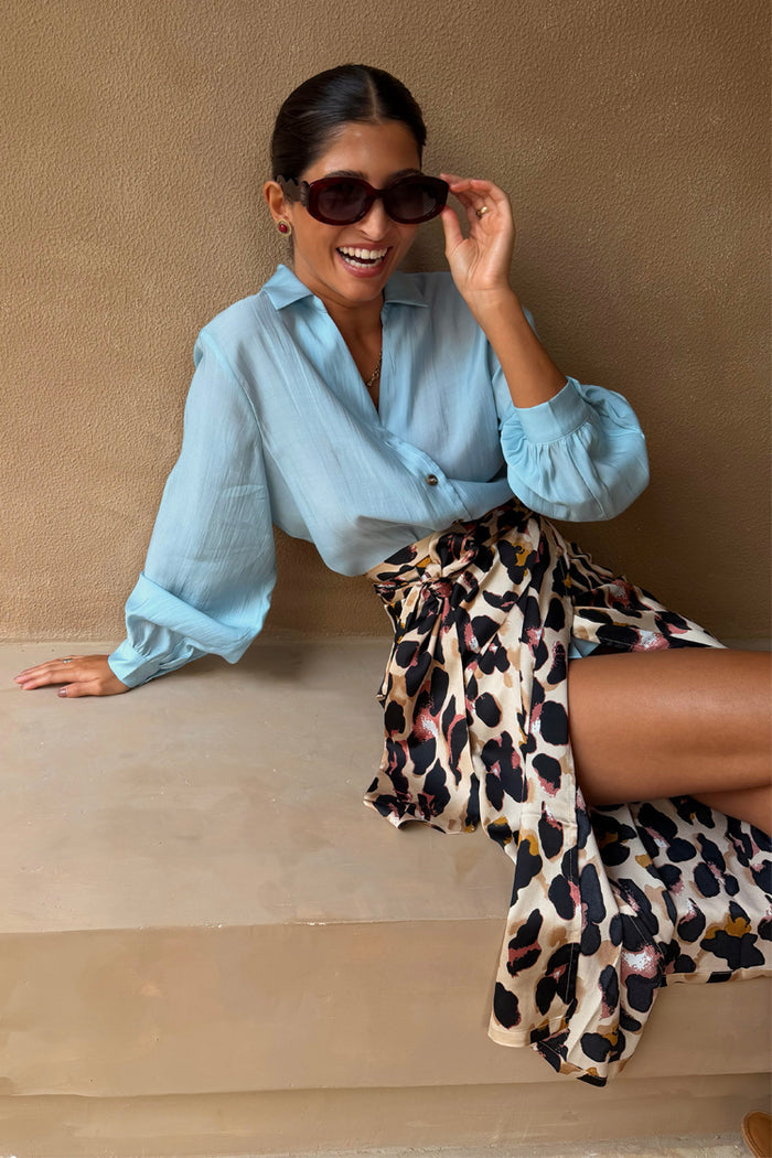 Iconic Brown Leopard Jaspre Skirt in sleek satin styled with a light blue shirt and sunglasses.