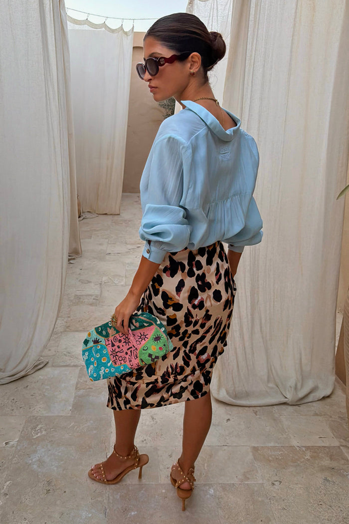 Iconic Brown Leopard Jaspre Skirt in a satin wrap style, paired with a light blue shirt and colourful clutch.