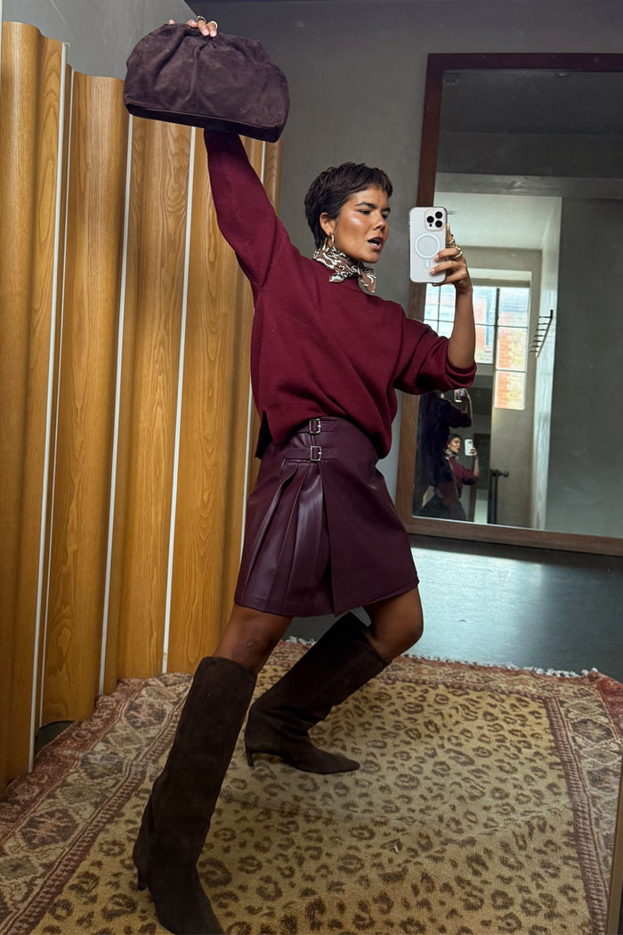 Burgundy vegan leather Mini Kilt Skirt with side pleats and buckles, styled with a jumper in a mirror selfie.