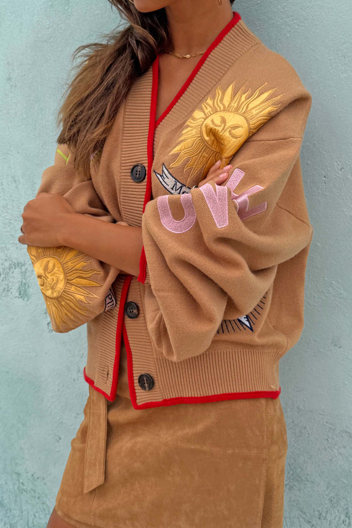 Camel Mystical Cardigan with sun embroidery, red trim and button-up front, styled with a tan skirt.