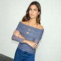 Charcoal Diaz Top in grey mesh with off-the-shoulder rouching and long sleeves, paired with blue denim jeans.