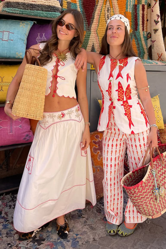 Cream and Red Pollenca Skirt with sun and palm embroidery, styled with a matching top and a woven straw bag.