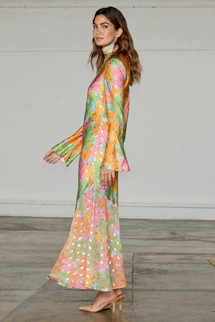 Multicoloured Floral Alaia Dress featuring gold flecks, bell sleeves and an asymmetric hem in a side profile.