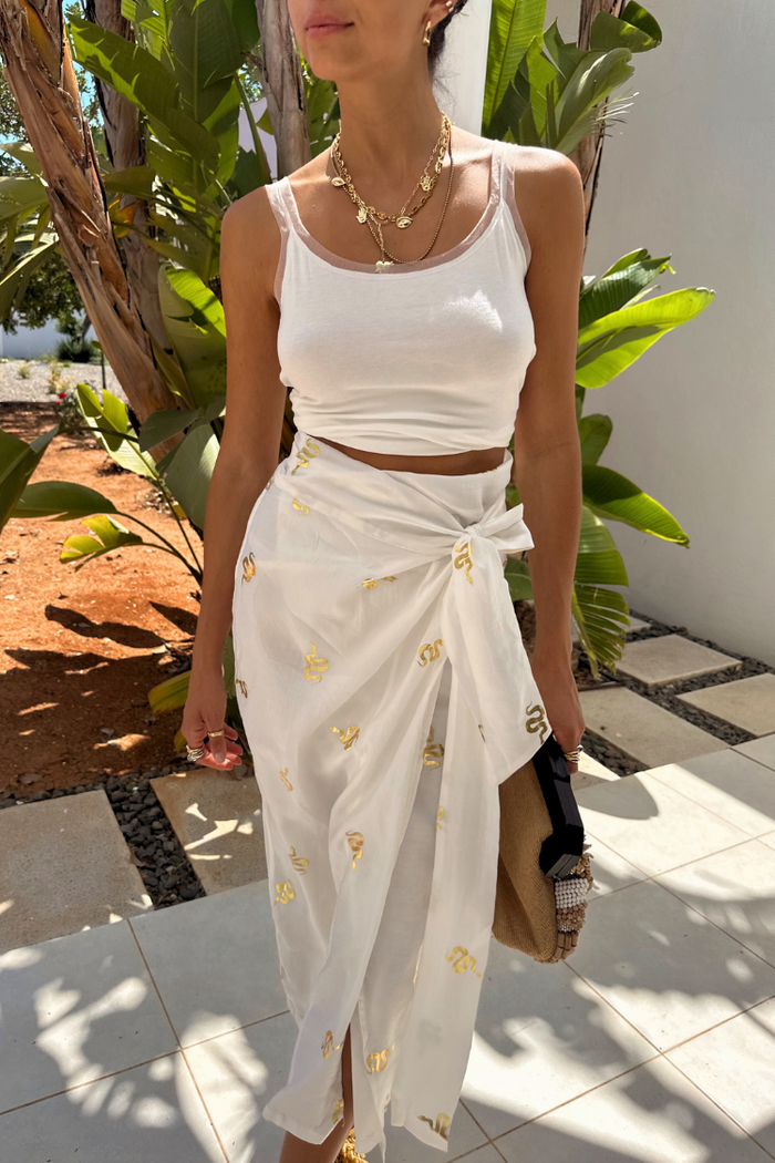 Gold Snake Jaspre Wrap Skirt in white with gold foil motifs, styled with a white top among palm trees.