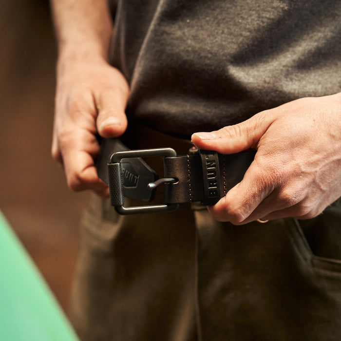 View 2 man putting on leather belt with orange stitching and embossed BRUNT logo in brown * 0