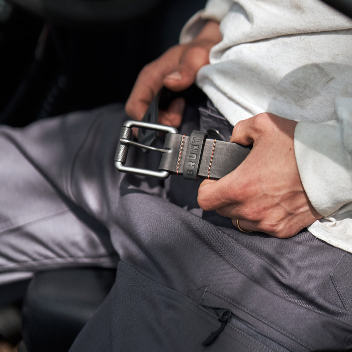 View 2 man putting on leather belt with orange stitching and embossed BRUNT logo in black * 1