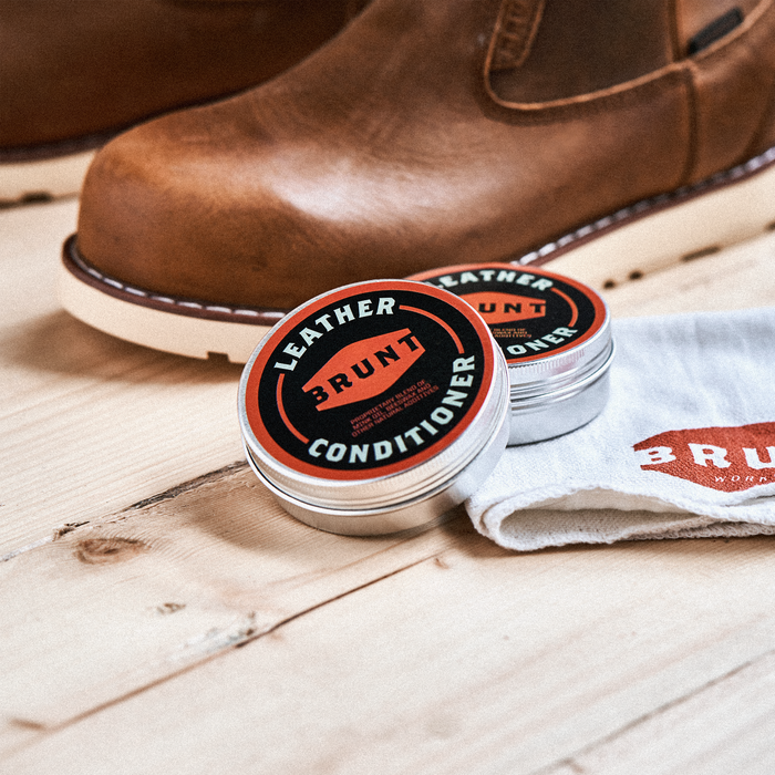 View 2 container of BRUNT leather work boot conditioner and shop rag with BRUNT logo in shop