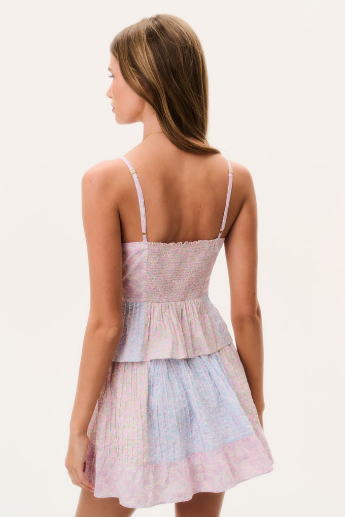 Woman wearing a pastel matching tank top and mini skirt with a white background