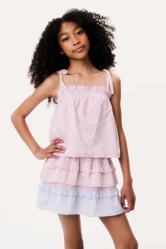 Young girl wearing a pink top and light blue tiered skirt on a white background