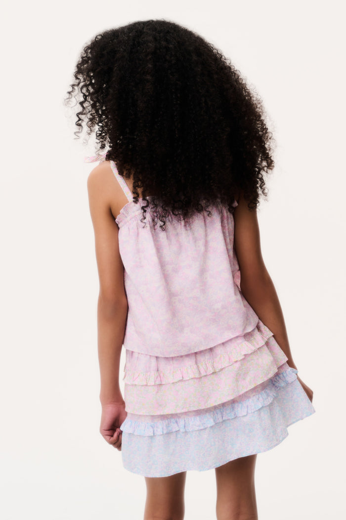 Back view of a child wearing a layered pink and white camisole and matching skirt on a white background