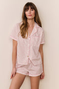 Woman wearing a pink floral pajama set against a beige background