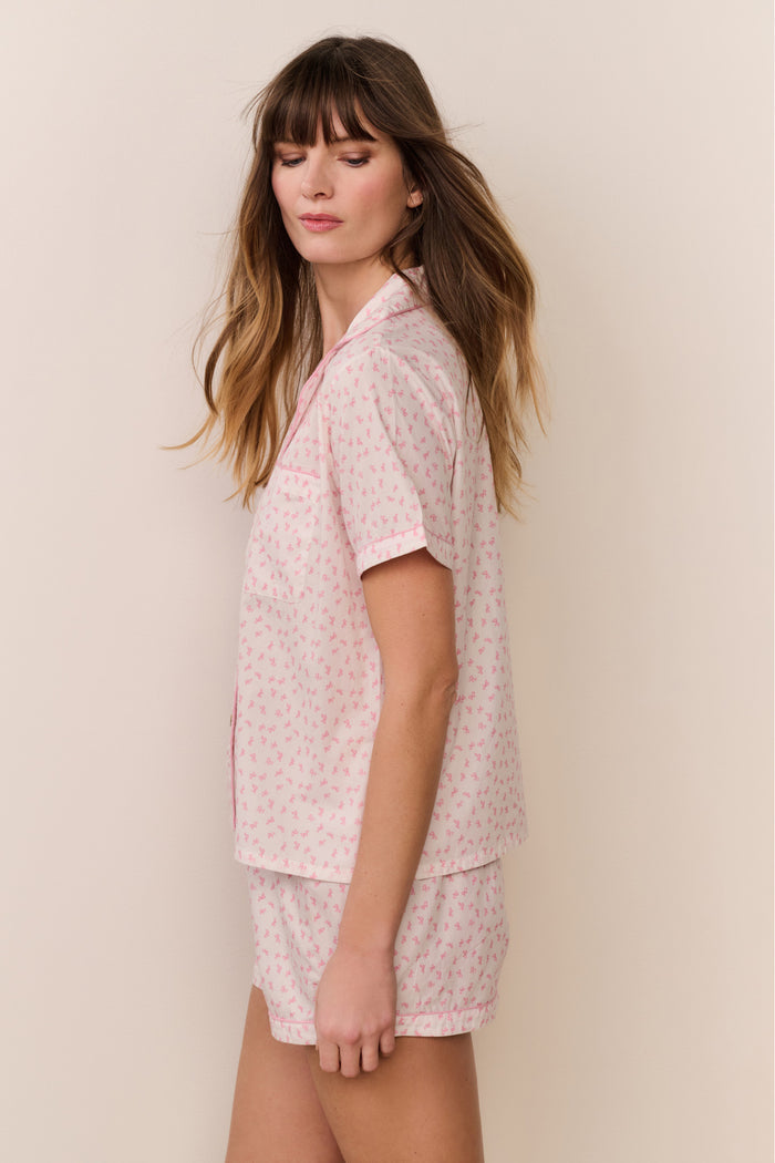 Woman wearing a pink floral pajama set against a beige background