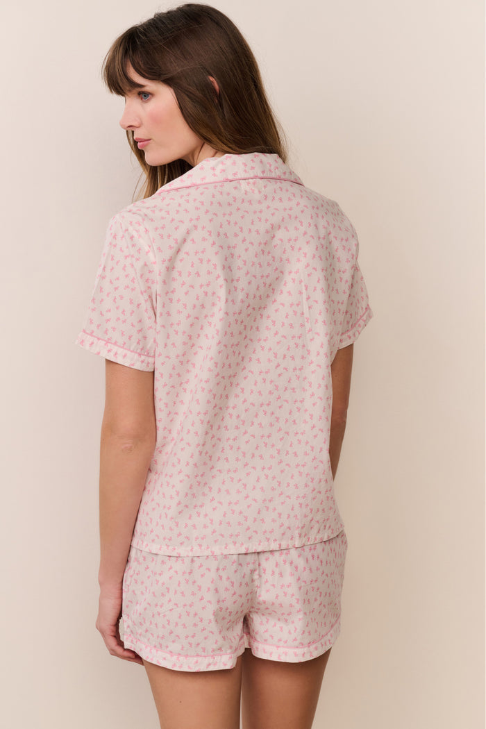 Woman wearing a pink floral pajama set against a plain background