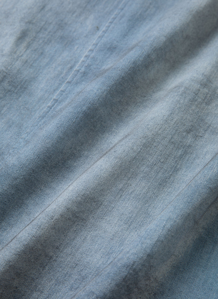 Close-up image of light blue denim fabric with visible textured lines and subtle shading, reminiscent of the FOUND Multi Patch Painters Work Jacket.