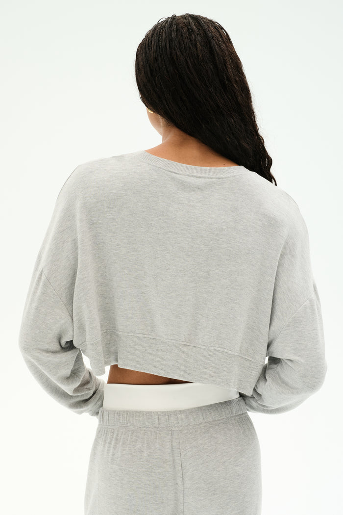 A person wears the SPLITS59 Noah Fleece Crop Sweatshirt in heather grey, paired with matching pants, made from soft modal spandex, photographed from behind against a plain white background.