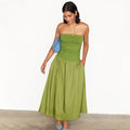 Olive Lola Mid-axi Dress featuring a ruched bandeau bodice and cotton skirt, styled with a blue clutch.