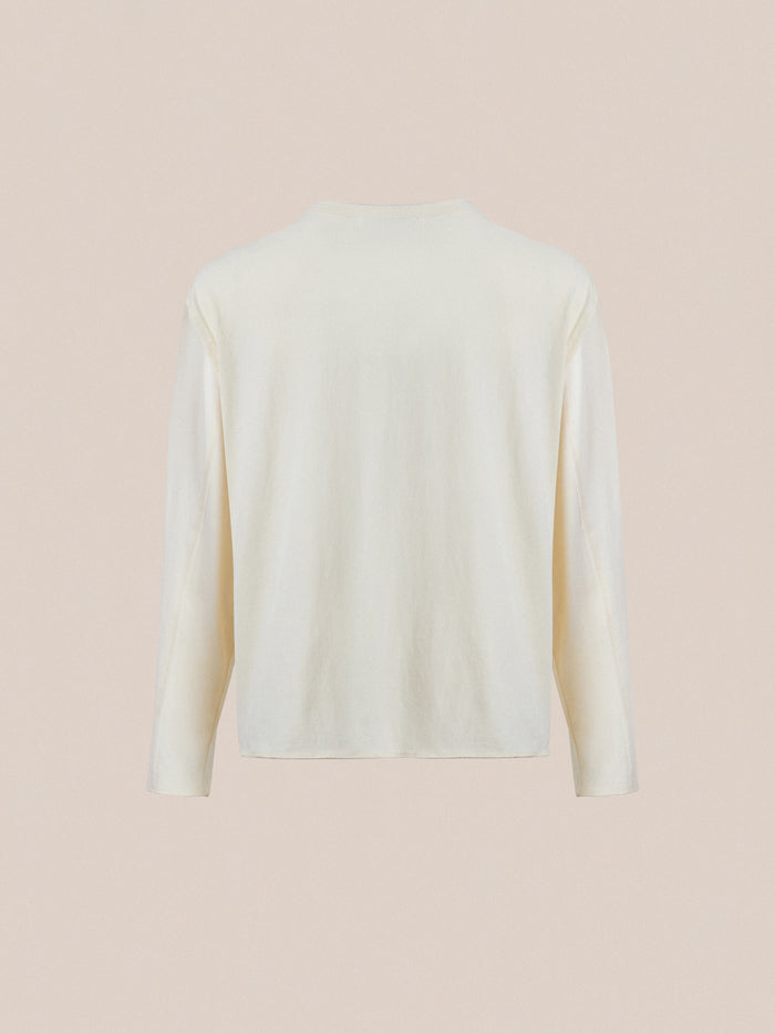 The FOUND Reversed LS Tee is a cream-colored, unisex long sleeve shirt with a distressed neckline, shown from the back against a plain beige background. Effortless style for any occasion.