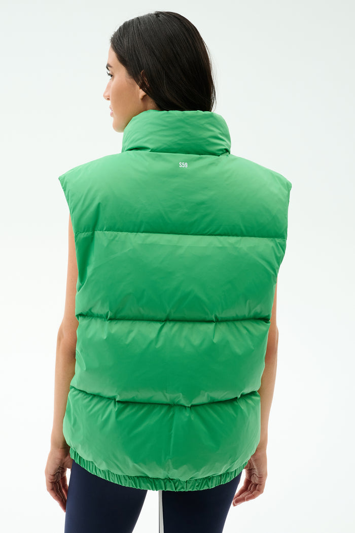 A person is shown from the back wearing the SPLITS59 Summit Nylon Puffer Vest in Grass, featuring "550" on the upper back—ideal for cool weather workouts—standing against a plain light background.