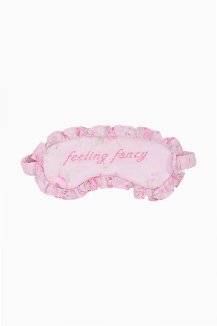 Pink sleep mask with floral pattern and 'feeling fancy' text on a white background