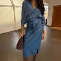 Teal vegan leather Jaspre wrap midi skirt styled with a blue button-down shirt and brown boots.