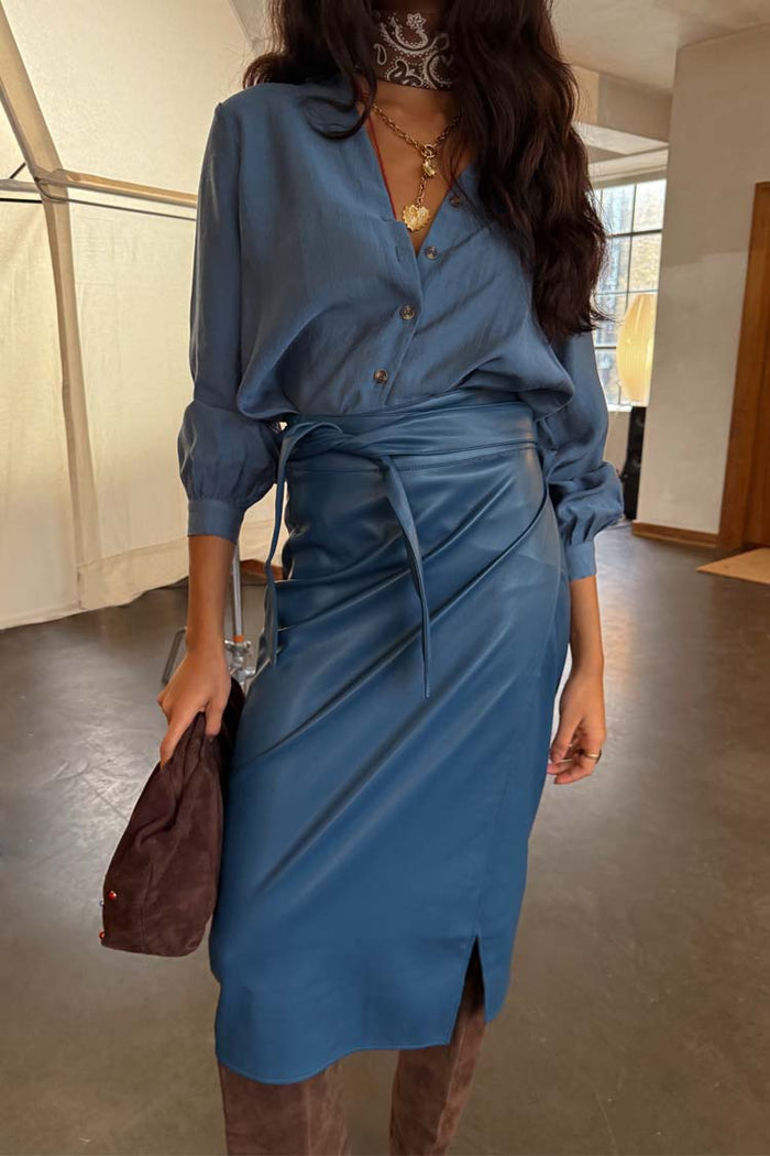 Teal Vegan Leather Jaspre wrap skirt styled with a blue button-up shirt and brown suede bag.