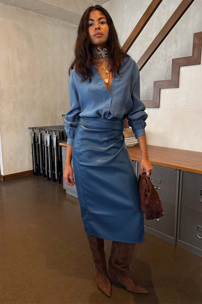 Teal Vegan Leather Jaspre Skirt styled with a blue long-sleeve shirt and brown suede boots.