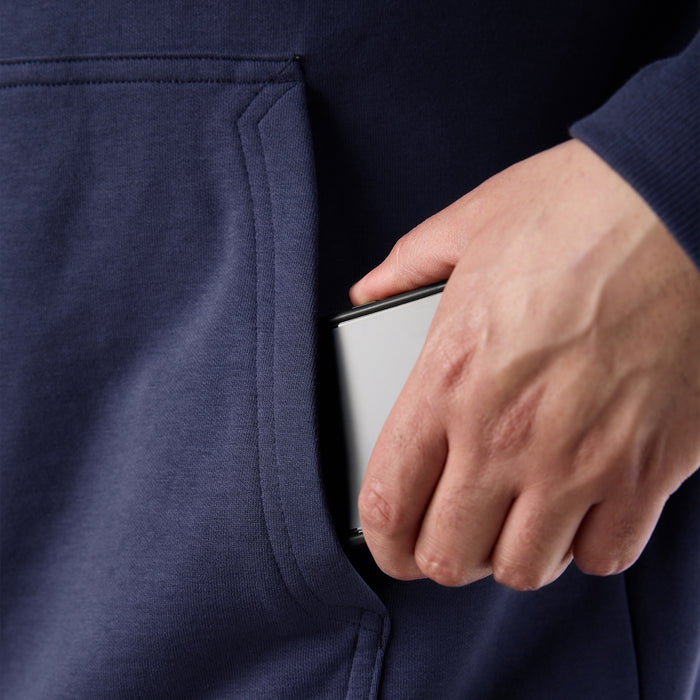 Man putting phone in oversized front pocket of BRUNT comfortable all-season levin work hoodie in navy * 0