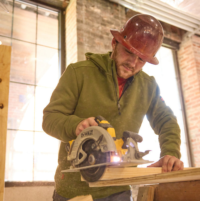 Man wearing BRUNT water resistant shevlin work quarter zip hoodie in hunter green using table saw on jobsite * 1