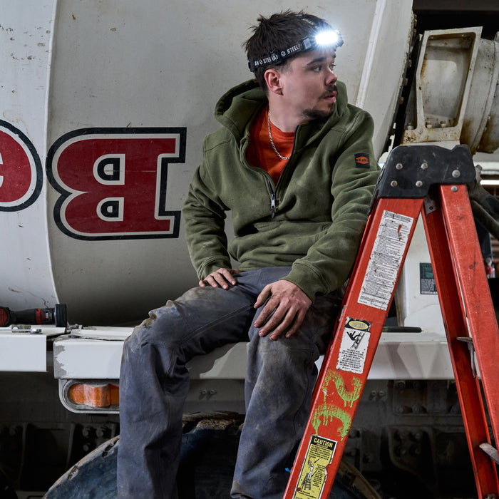 Man wearing BRUNT water resistant shevlin work quarter zip hoodie in hunter green using table saw on jobsite