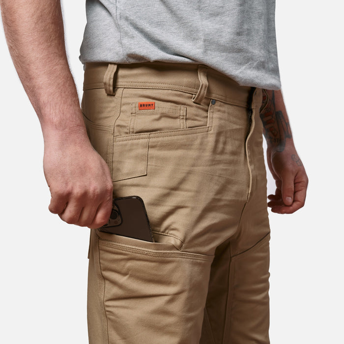 Putting phone in tech pocket of BRUNT water resistant double-knee torra hd work pant in tan * 0