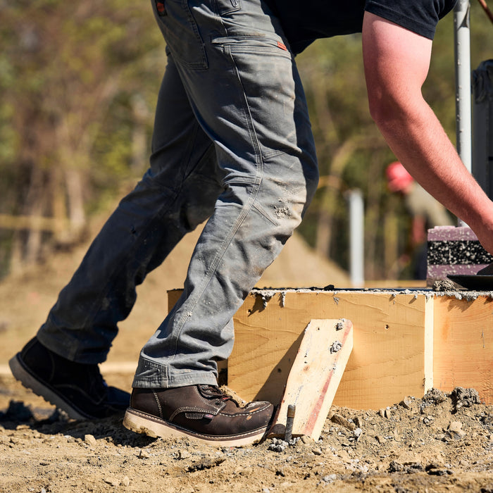 Man on jobsite wearing the BRUNT water resistant stretch torra work pant in charcoal
