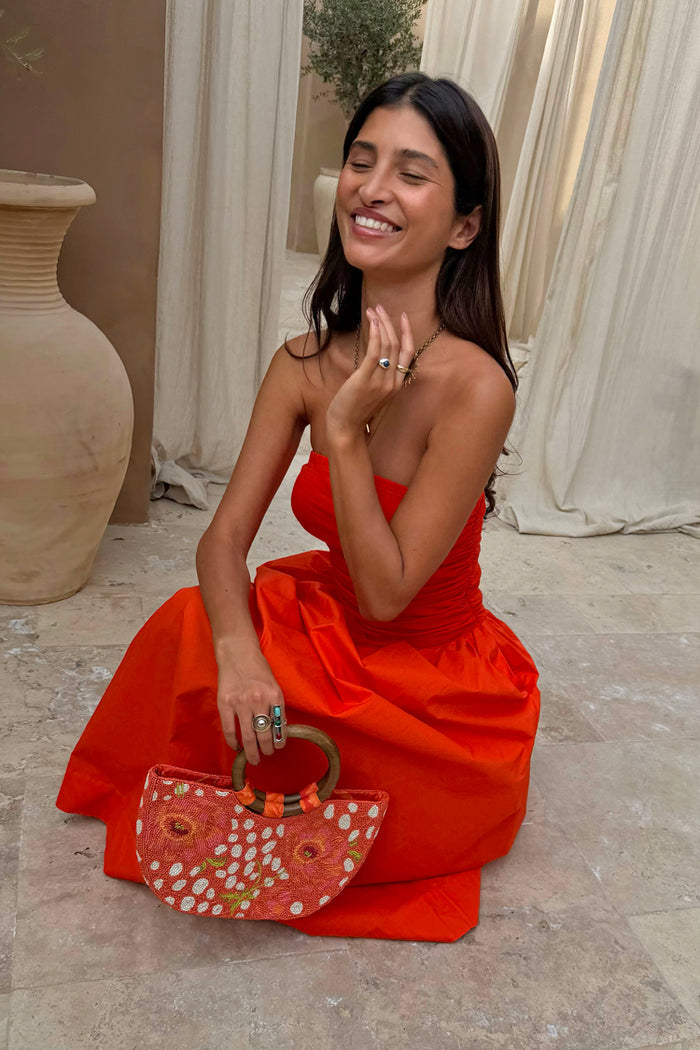 Red Tomato Lola Mid-axi Dress featuring a ruched strapless bodice and full cotton skirt, styled with a beaded bag.
