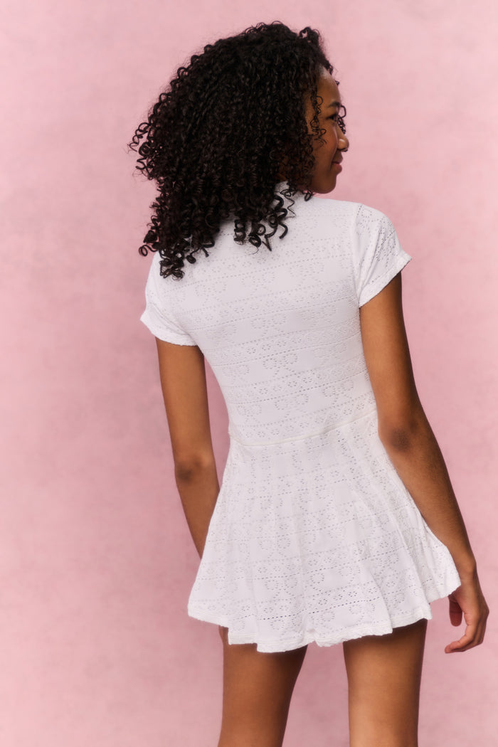Woman wearing a white lace dress against a pink background