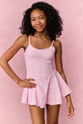 Young girl wearing a pink checkered dress against a pink background