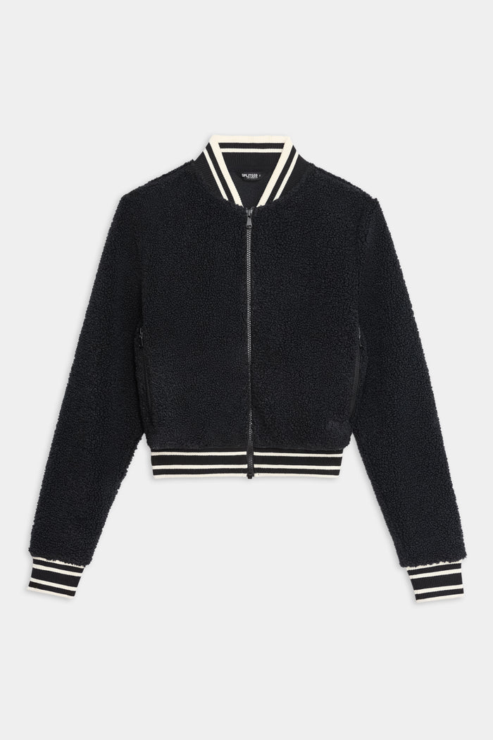 The SPLITS59 Willa Sherpa Jacket - Black is a cozy baseball-style bomber with a front zipper and white-striped ribbed trim—ideal for winter workouts. Shown here against a white background.